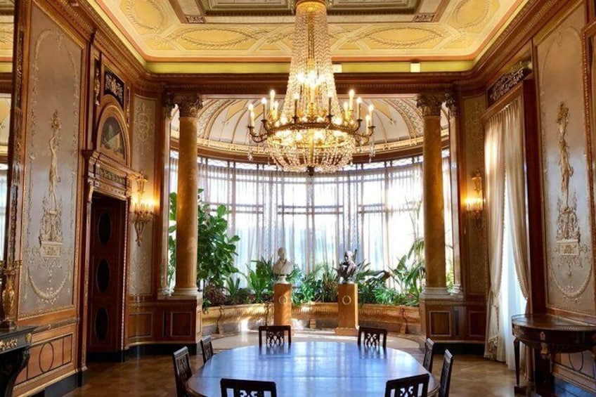 An opulent room with a large chandelier, ornate columns, and a round table. 4