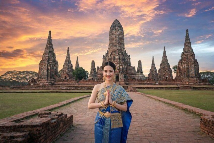 A person in traditional attire standing in front of ancient temple ruins with a sunset sky. 2