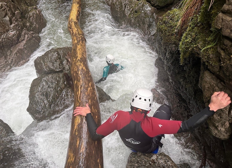 A person rappelling down a rocky waterfall with another person in the background. 1