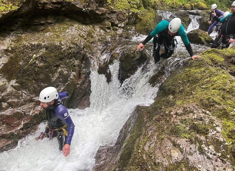 A group of people rappelling down a rocky waterfall. 5