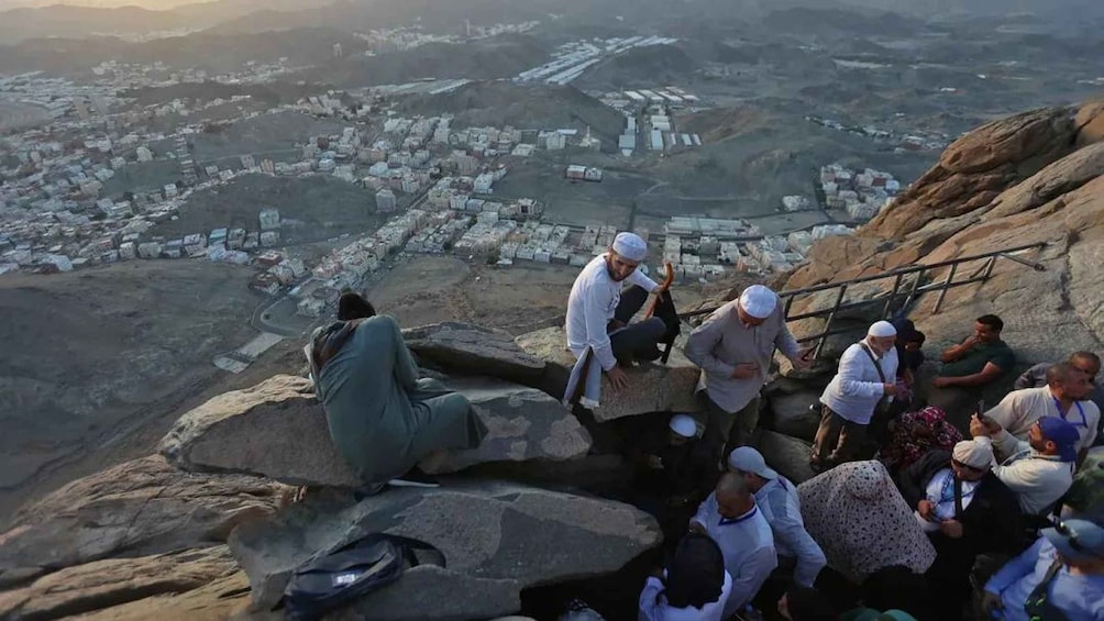 A group of people sitting on rocks overlooking a cityscape. 2