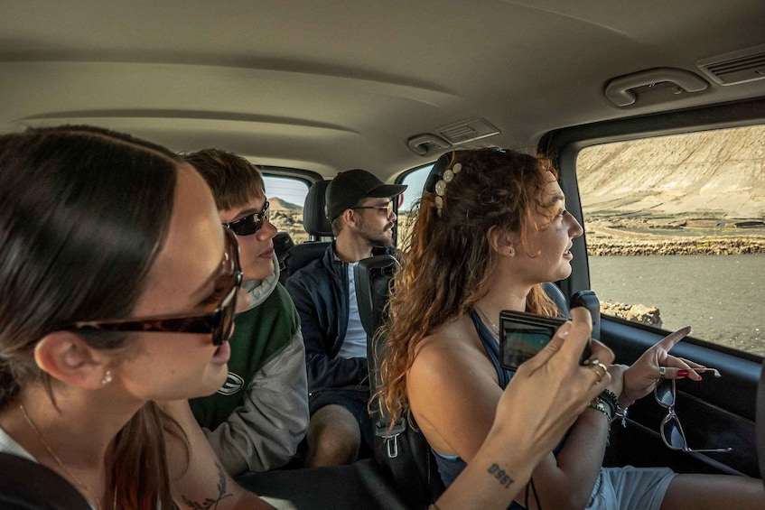 Four people in a vehicle, with a river and rocky landscape visible through the window. 4