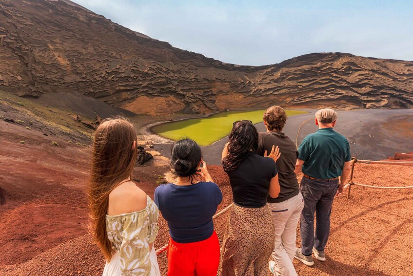 A group of people observing a volcanic crater with a green lake. 2