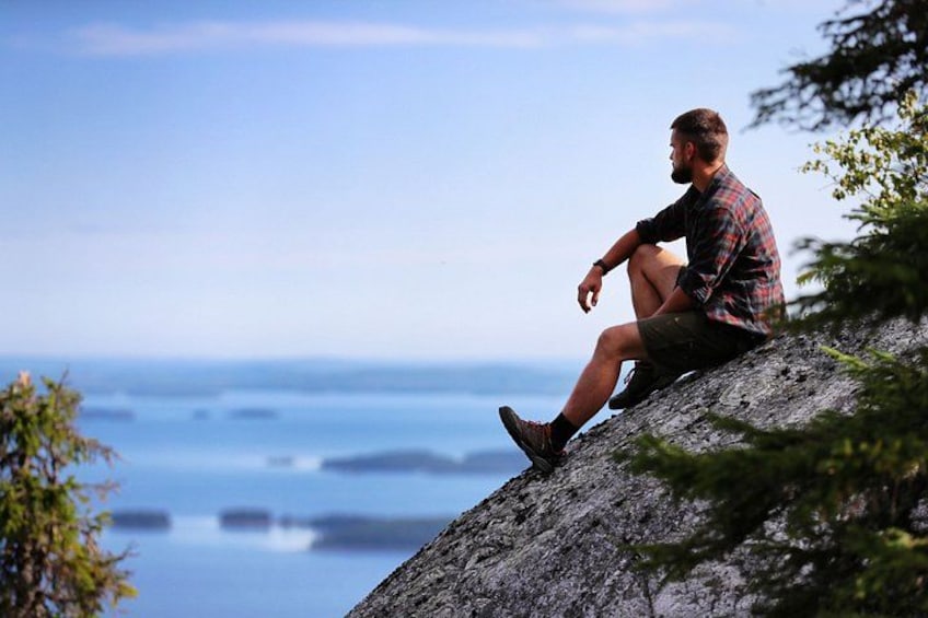A person sitting on a rock by the sea. 1