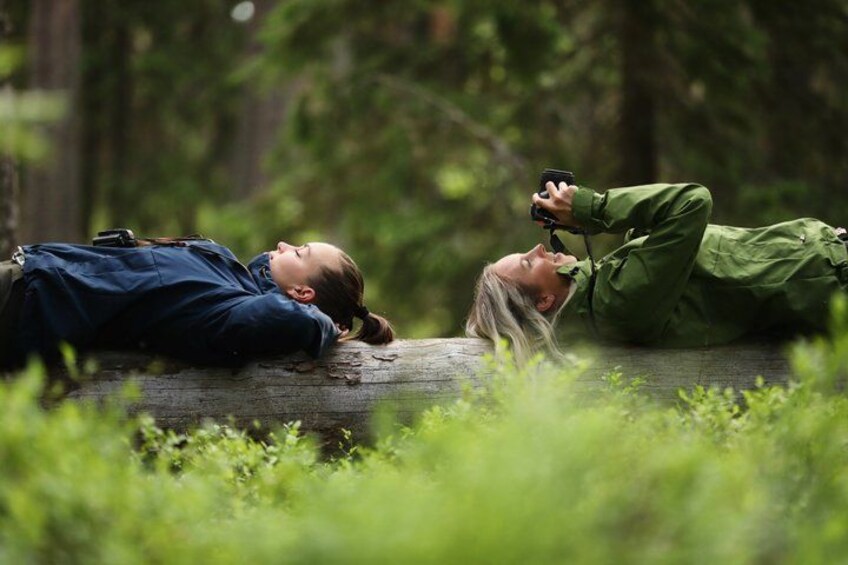 Two people lying on the ground in a forest, one with a camera. 2