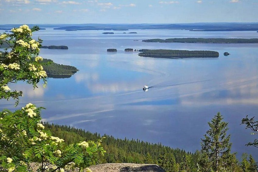 A lake with several islands, a boat, and surrounding forest. 2