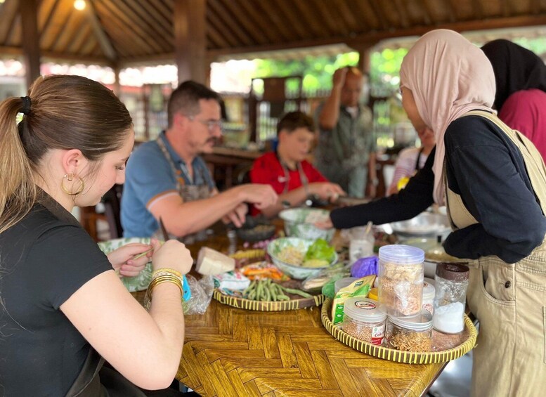 A group of people at a food stall with various food items and containers on the table. 5