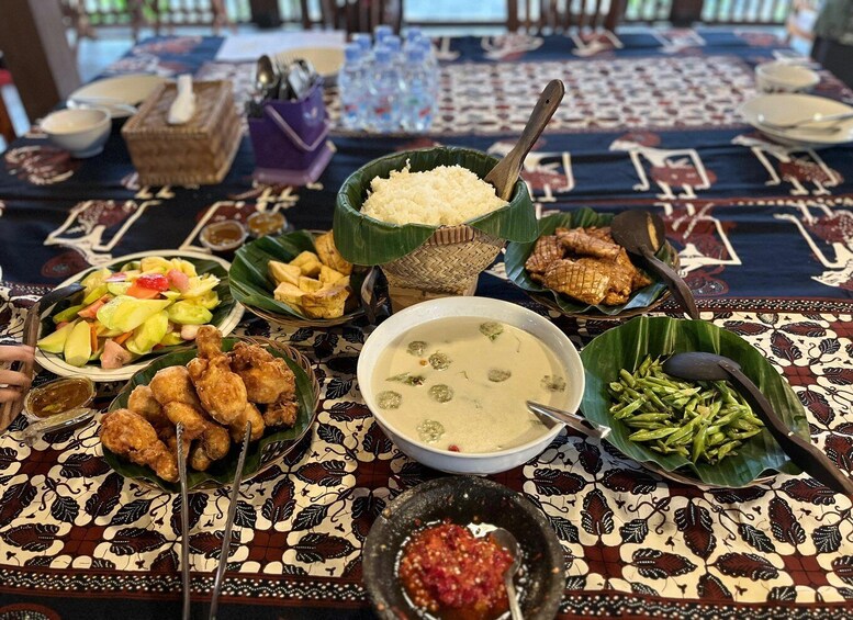 A table with various dishes including rice, fried chicken, a salad, and a bowl of soup. 1