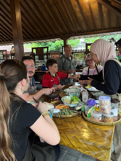 A group of people around a table with food and cooking utensils. 4