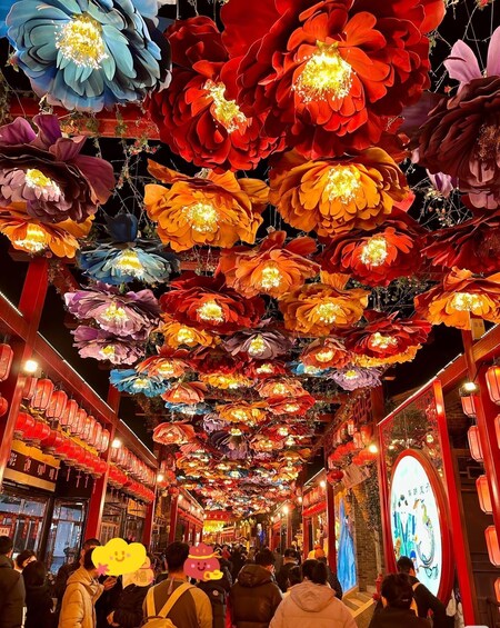 A corridor with hanging paper flowers and red lanterns. 3
