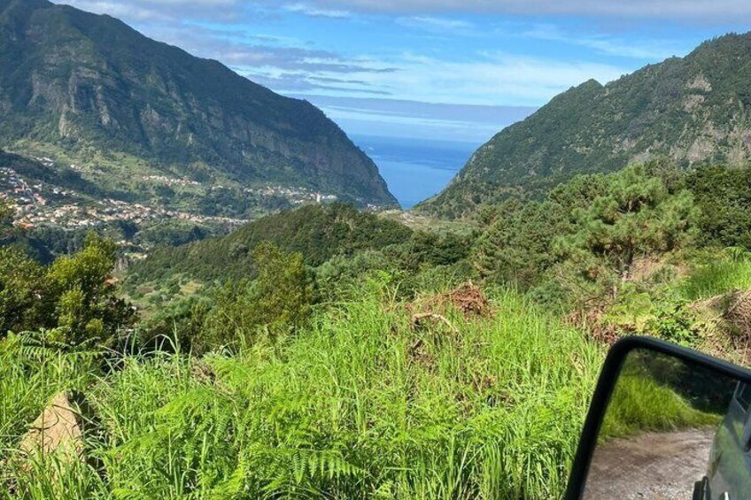 A mountainous landscape with a valley, a road, and a body of water in the distance. 5