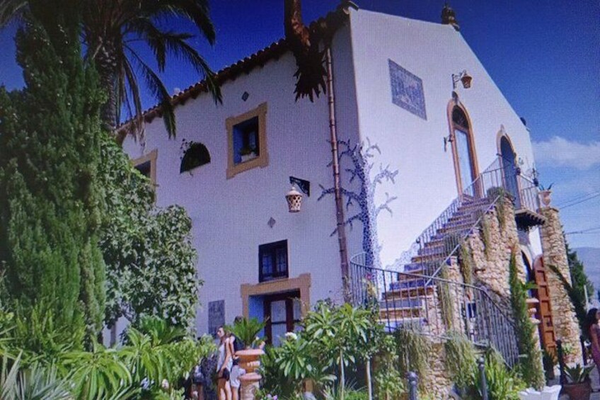 A building with a stucco exterior, a stone staircase, and a palm tree in the foreground. 5