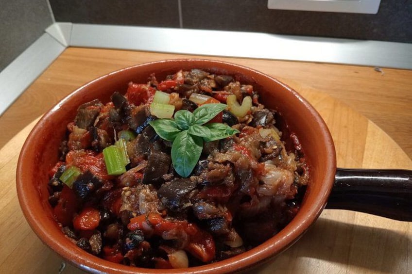 A bowl of stew with vegetables and meat, garnished with a basil leaf. 3