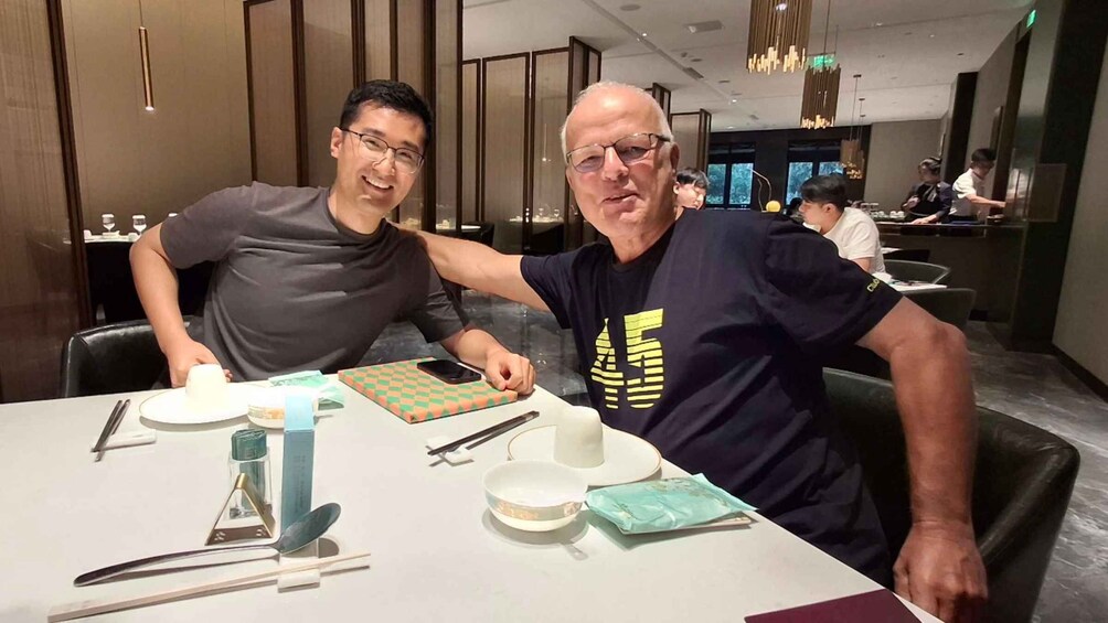 Two people seated at a table in a modern restaurant with a checkered tablecloth, chopsticks, and a smartphone on the table. 5