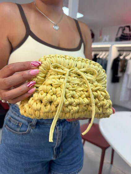 A person holding a yellow braided bag. 3