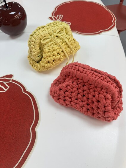 A table with crocheted items in yellow and red, and a red apple. 4