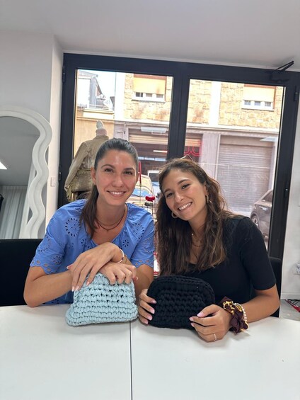 Two women sitting at a table with crocheted items. 5