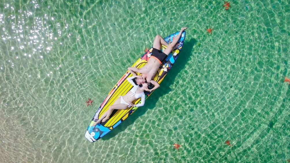 A person lying on a colorful inflatable raft in clear water. 4