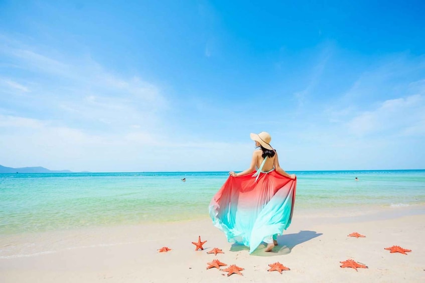 A person standing on a beach with starfish scattered around. 5