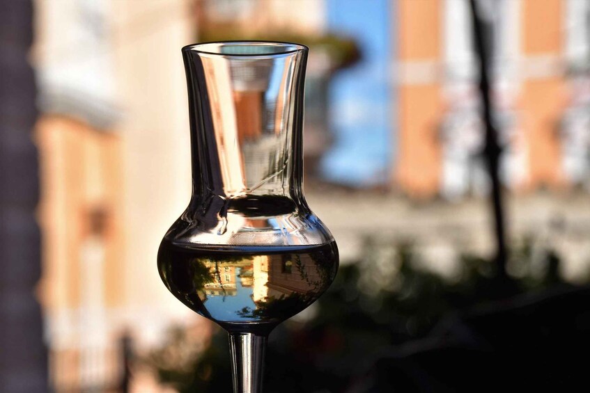 A clear glass vase with a narrow neck and a wider base, reflecting buildings and trees in the background. 5
