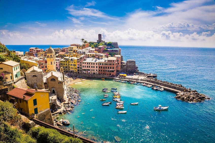 A coastal town with colorful buildings, a clear blue sea, and boats docked at the harbor. 5