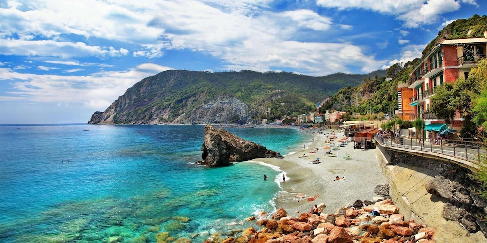 A coastal town with clear turquoise waters, a rocky outcrop, and colorful buildings along the beach. 4