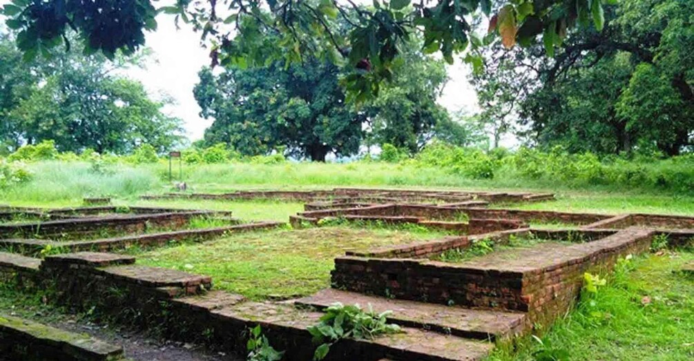 Ancient brick ruins with a circular layout, surrounded by lush greenery and trees. 4