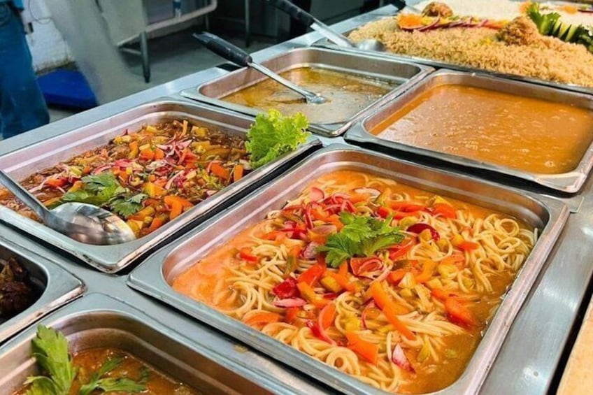 A buffet with various dishes including noodles, vegetables, and a meat dish. 5