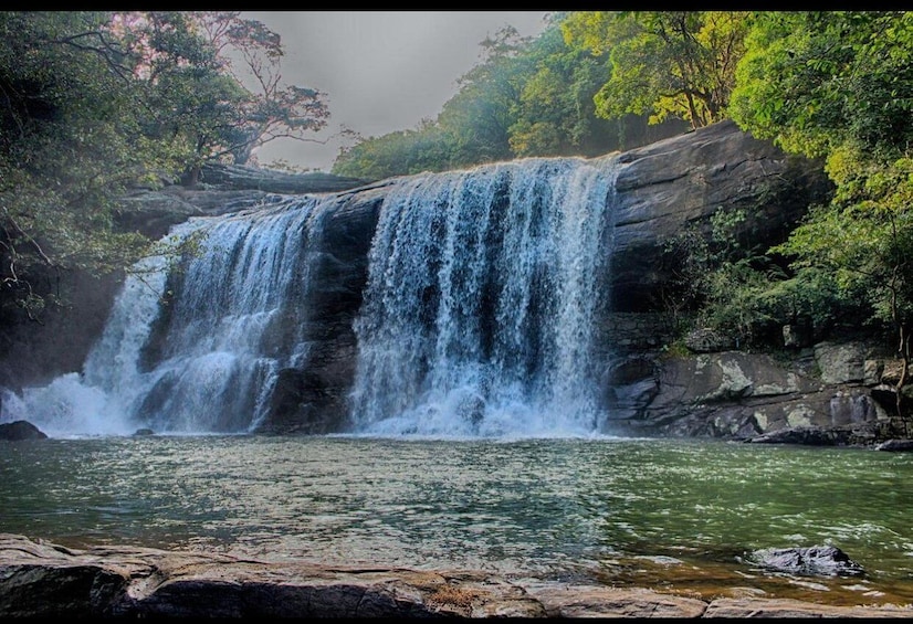 A waterfall cascading over rocks into a river, surrounded by lush greenery. 1