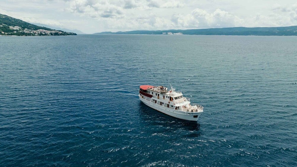 A white boat with a red roof sailing on a calm sea. 5