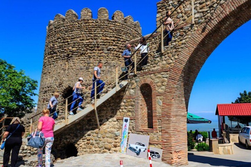 A stone castle with a large arched bridge and people climbing it. 5