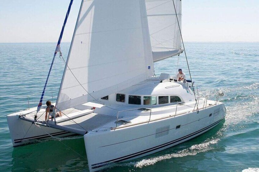 Un voilier blanc avec deux personnes à bord, naviguant sur une mer calme. 1