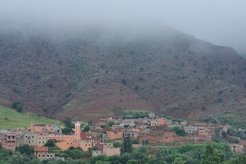 A village with buildings and a mosque, surrounded by hills and greenery. 3