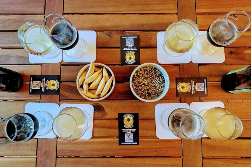 A wooden table with glasses of beverages, a bowl of snacks, and QR codes. 4