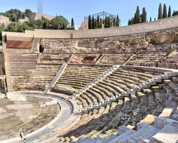 An ancient amphitheater with tiered seating and a central stage area. 1