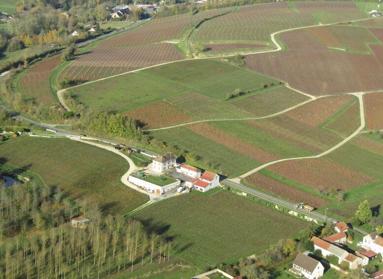 An aerial view of a rural landscape with fields, a road, and a cluster of buildings. 2