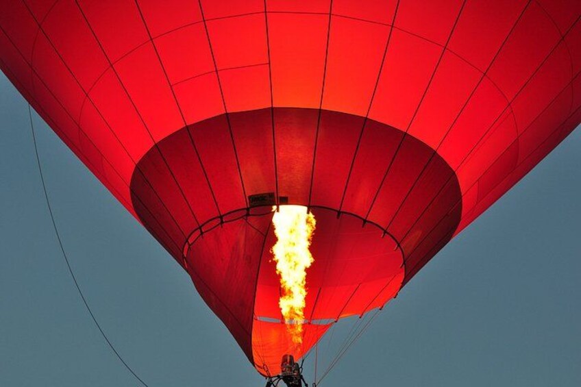 A hot air balloon with a bright flame at the bottom, against a clear sky. 5