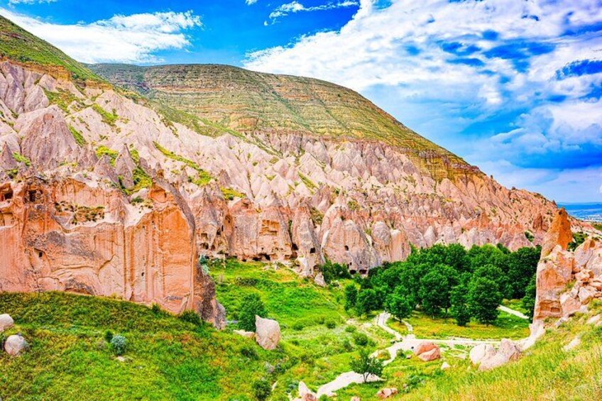 A rugged landscape with rocky formations, green vegetation, and a clear sky. 2