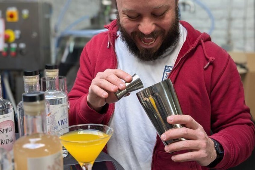 Iemand giet een gele vloeistof in een metalen shaker. 2
