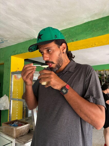 A person wearing a green cap and a grey shirt, eating from a white bowl. 4