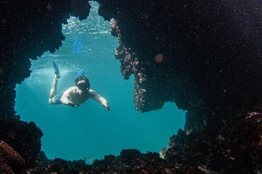 A person scuba diving in a clear blue underwater cave. 5