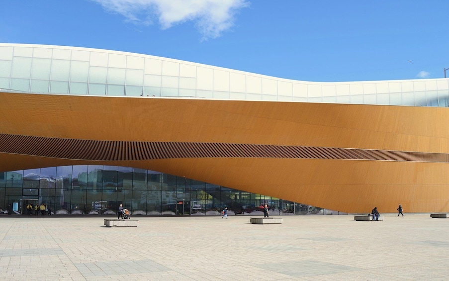 A modern building with a curved, wooden overhang and large glass windows. 5