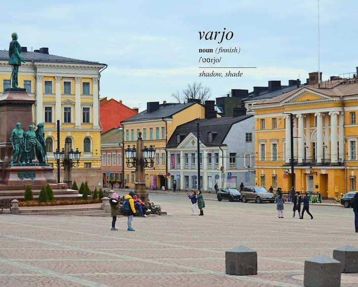 A square with a statue, buildings, and people. 1