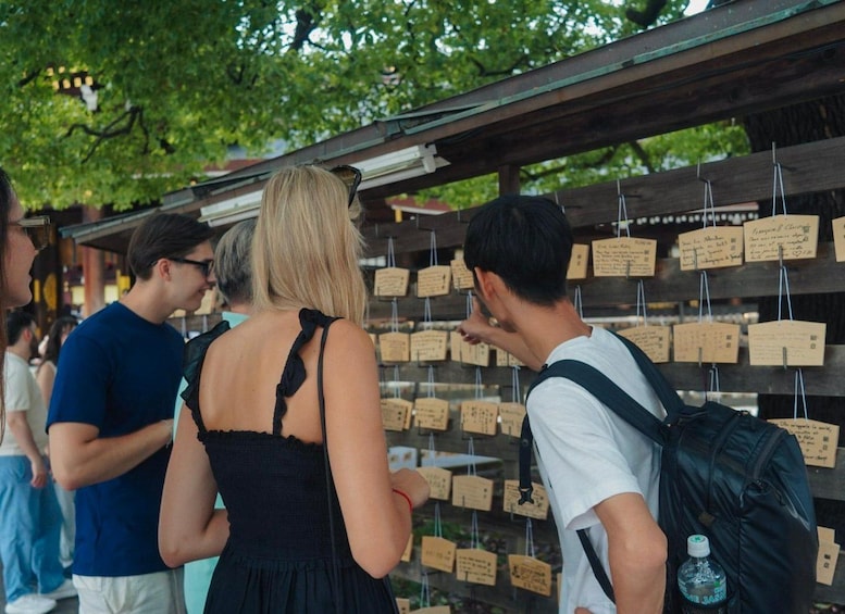People standing at a wooden structure with cards attached to it. 3