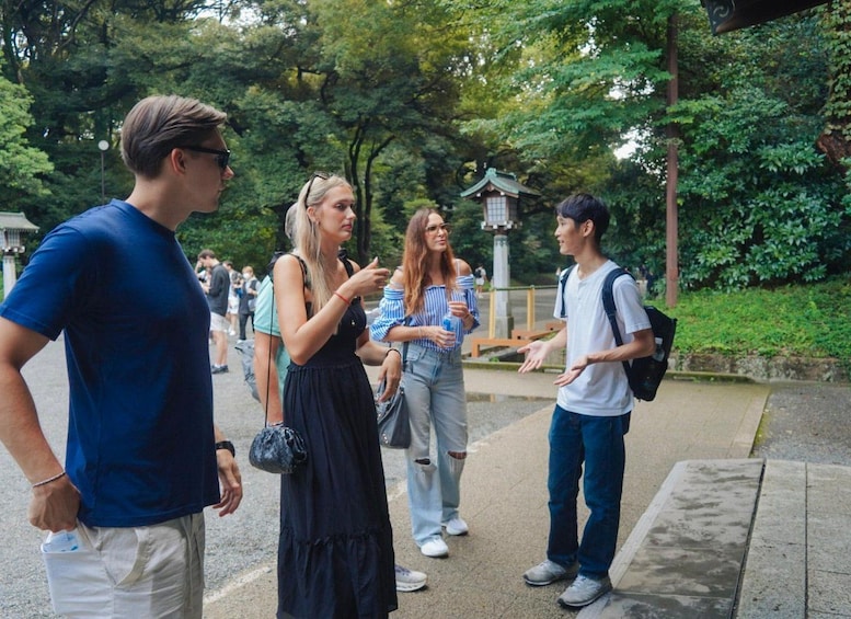 A group of people standing and conversing in a park with trees and a traditional Japanese structure in the background. 2