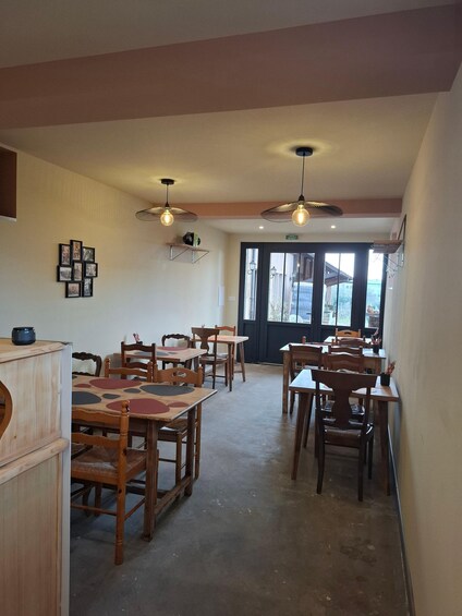 A restaurant interior with wooden tables and chairs, pendant lighting, and a view through the door. 3