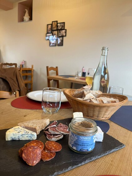 A table with cheese, cured meats, a bottle, and a jar of jam. 2