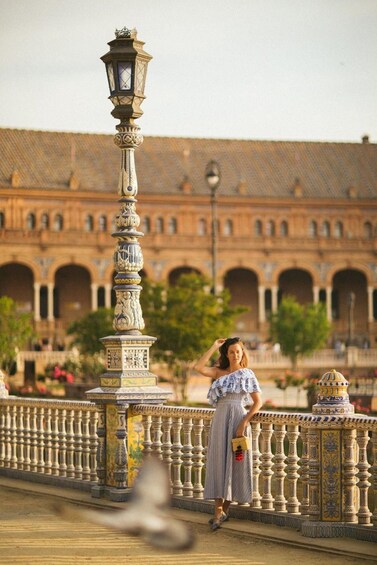 A woman standing on a bridge with ornate lamp posts and a historic building in the background. 3