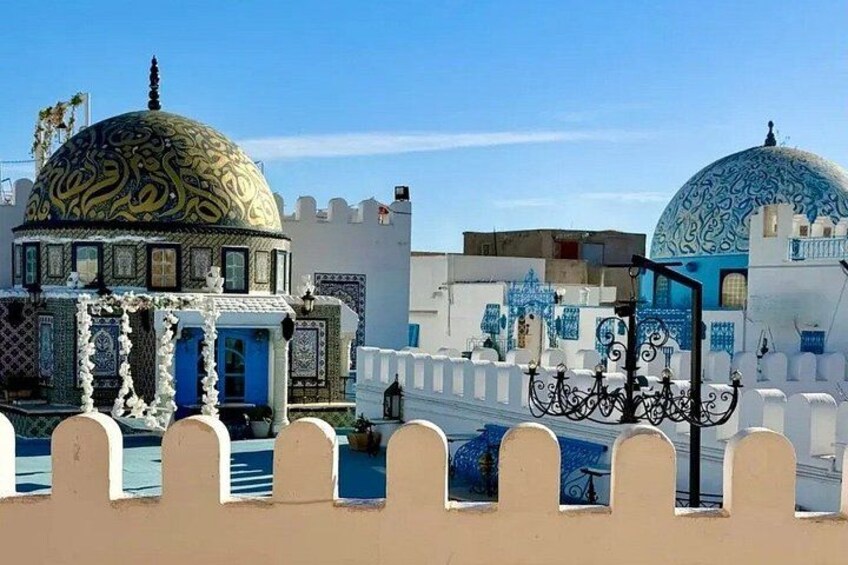 Un bâtiment traditionnel doté d’un dôme et de motifs complexes, un mur blanc agrémenté d’éléments bleus et une porte en métal décorative. 4