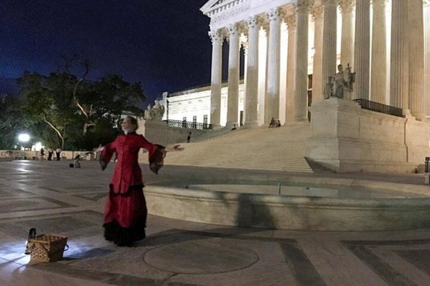 A person in a red dress performing in front of a classical building with columns. 2